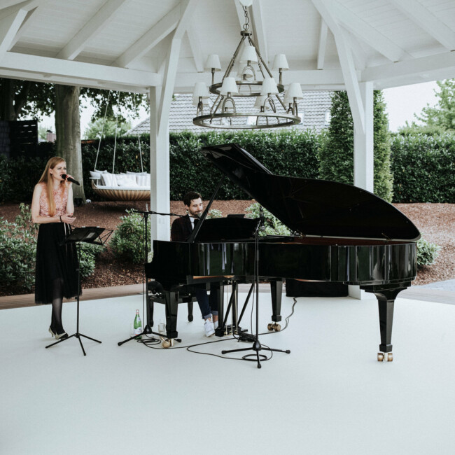 Pianist spiel Klavier, Sängerin singt dazu auf der Bühne