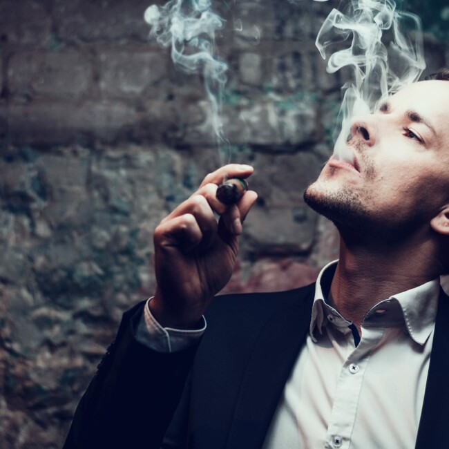 Mann im Anzug raucht eine Corrida Zigarre