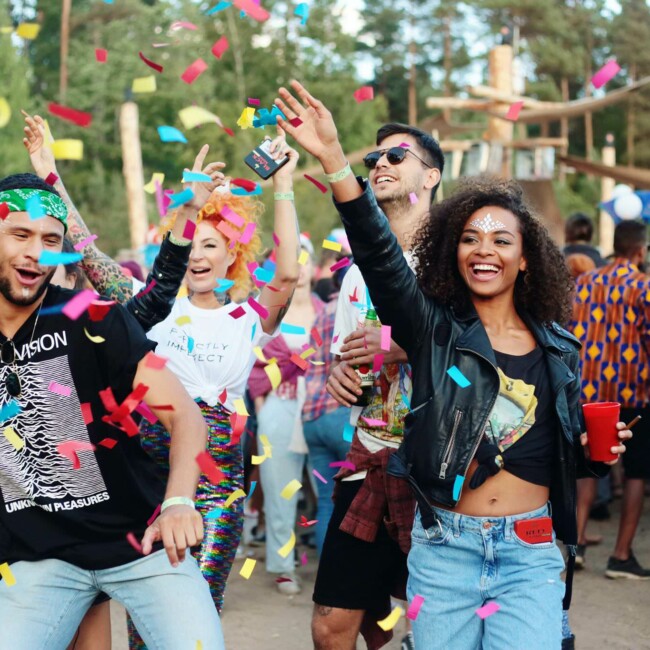 Menschen auf einem Festival werfen buntes Konfetti